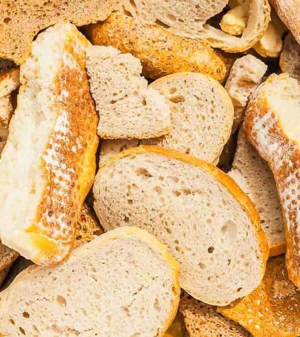 Various pieces of white and brown bread, some sliced and some broken, piled together in a close-up view.