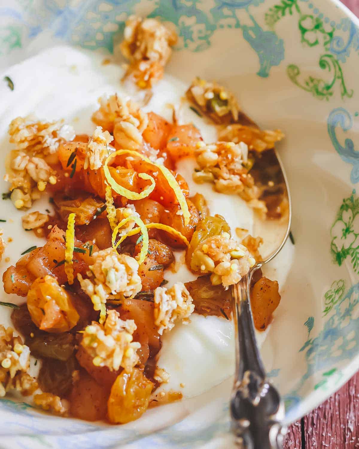 Yogurt bowl with apple compote and granola with a silver spoon.
