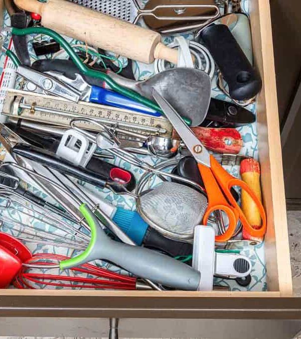 A kitchen drawer filled with assorted utensils and tools, including scissors, peelers, whisks, a grater, a thermometer, a rolling pin, and various other kitchen gadgets.