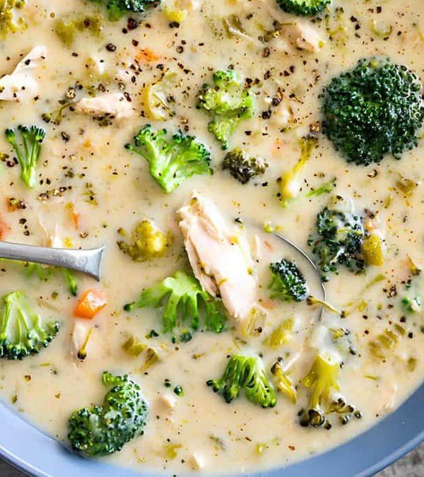 A bowl of creamy broccoli soup with chunks of broccoli and other vegetables, served with a spoon.