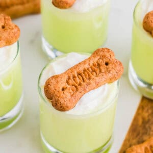 Small glasses filled with a Scooby shots topped with whipped cream and a Scooby bone-shaped cookie.