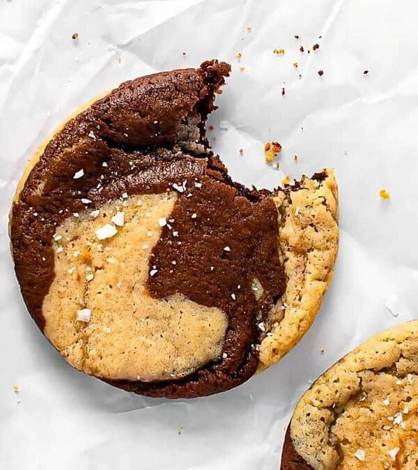 A marbled cookie with a bite taken out, sprinkled with salt, rests on parchment paper.