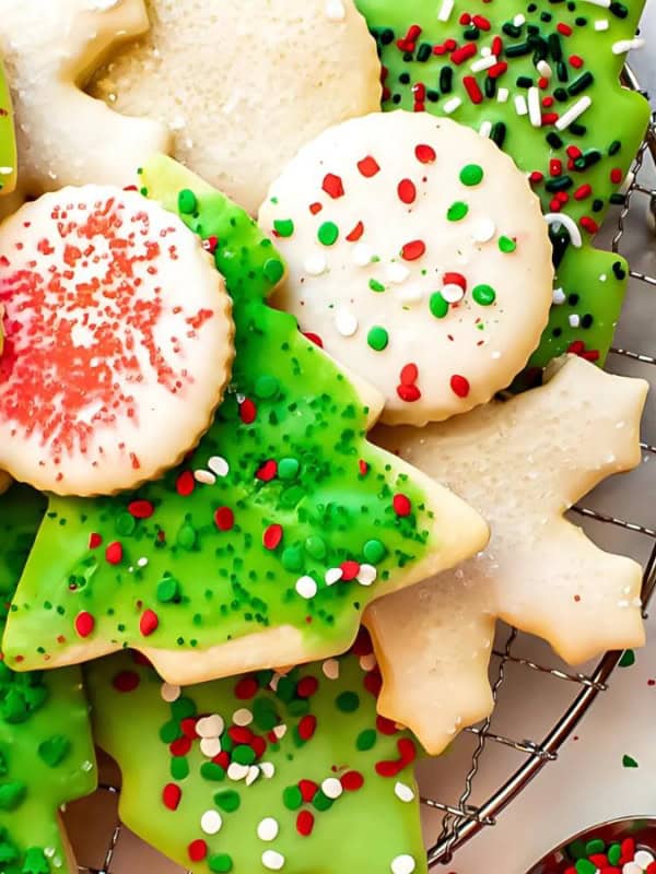 A variety of Christmas sugar cookies, including trees, stars, and circles decorated with green, red, and white frosting and sprinkles.