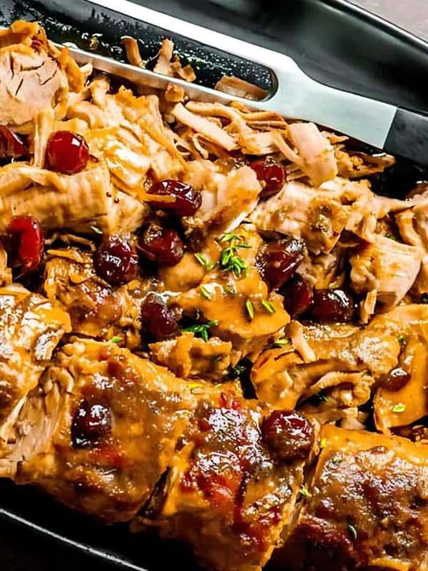 Juicy cranberry pork tenderloin garnished with slices of lemon on the side.