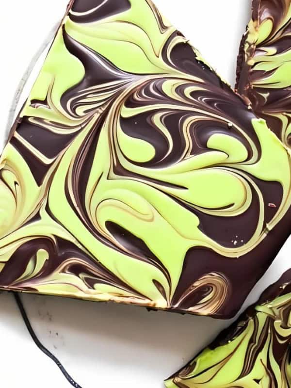 The image shows a plate of mint chocolate bark. The bark is made with dark chocolate, white chocolate, and mint extract. It is broken into pieces and is ready to be eaten.