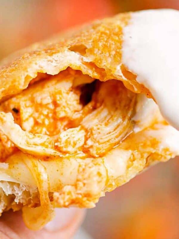 Buffalo chicken calzone held in a hand and dipped in ranch or blue cheese.