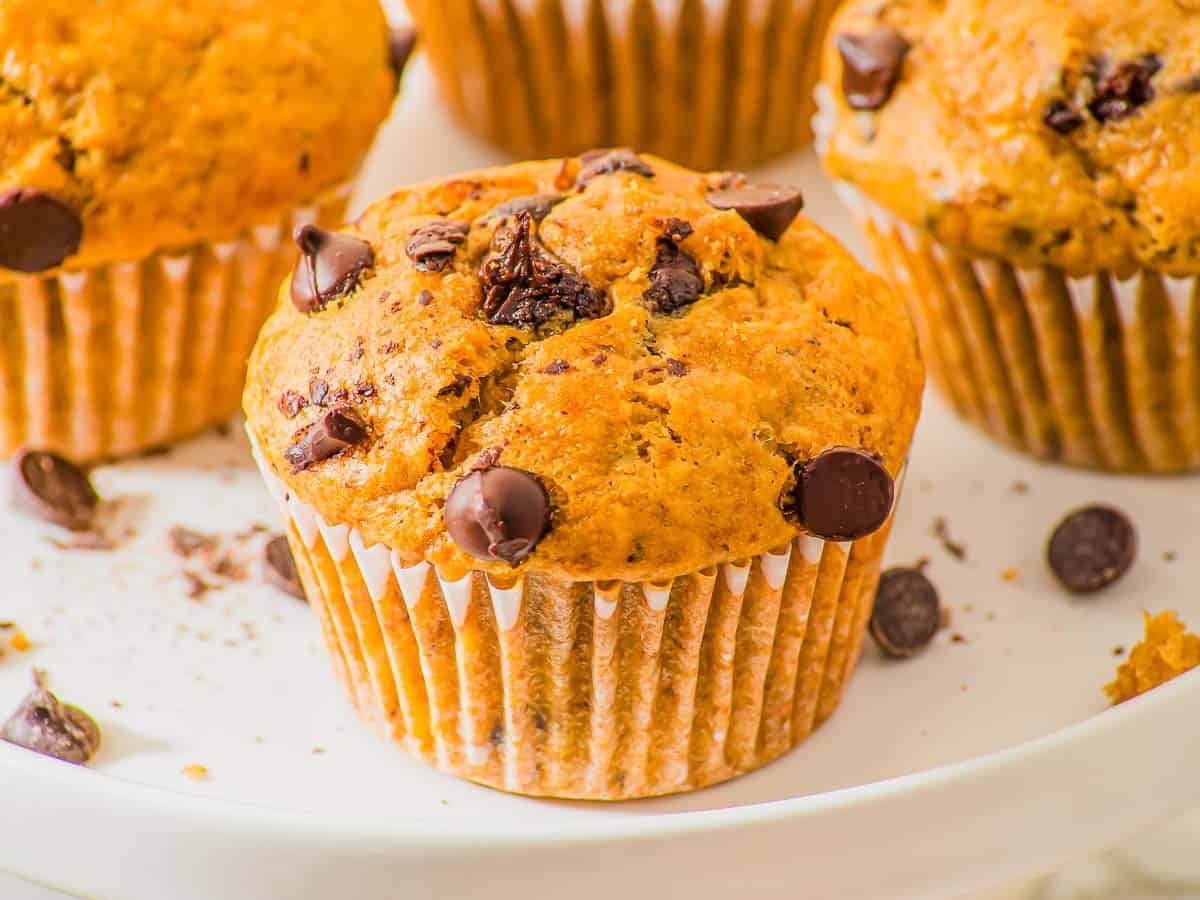 A close-up shows a single peanut butter banana muffin with chocolate chips.