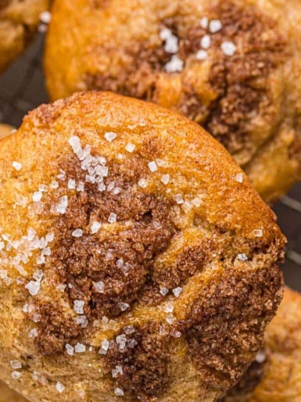 Close-up of freshly baked cookies on a cooling rack. The cookies are sprinkled with coarse sugar and have a golden-brown color with patches of darker, crumbly topping.