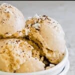 A close-up of scoops of coffee ice cream in a white bowl, sprinkled with grated coconut and ground coffee. The text "COFFEE ICE CREAM" is at the top, and "www.RUNNINGTOTHEKITCHEN.com" is at the bottom.