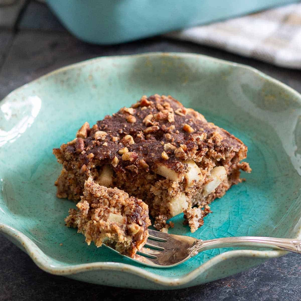 A piece of apple cinnamon cake on a plate with a fork.