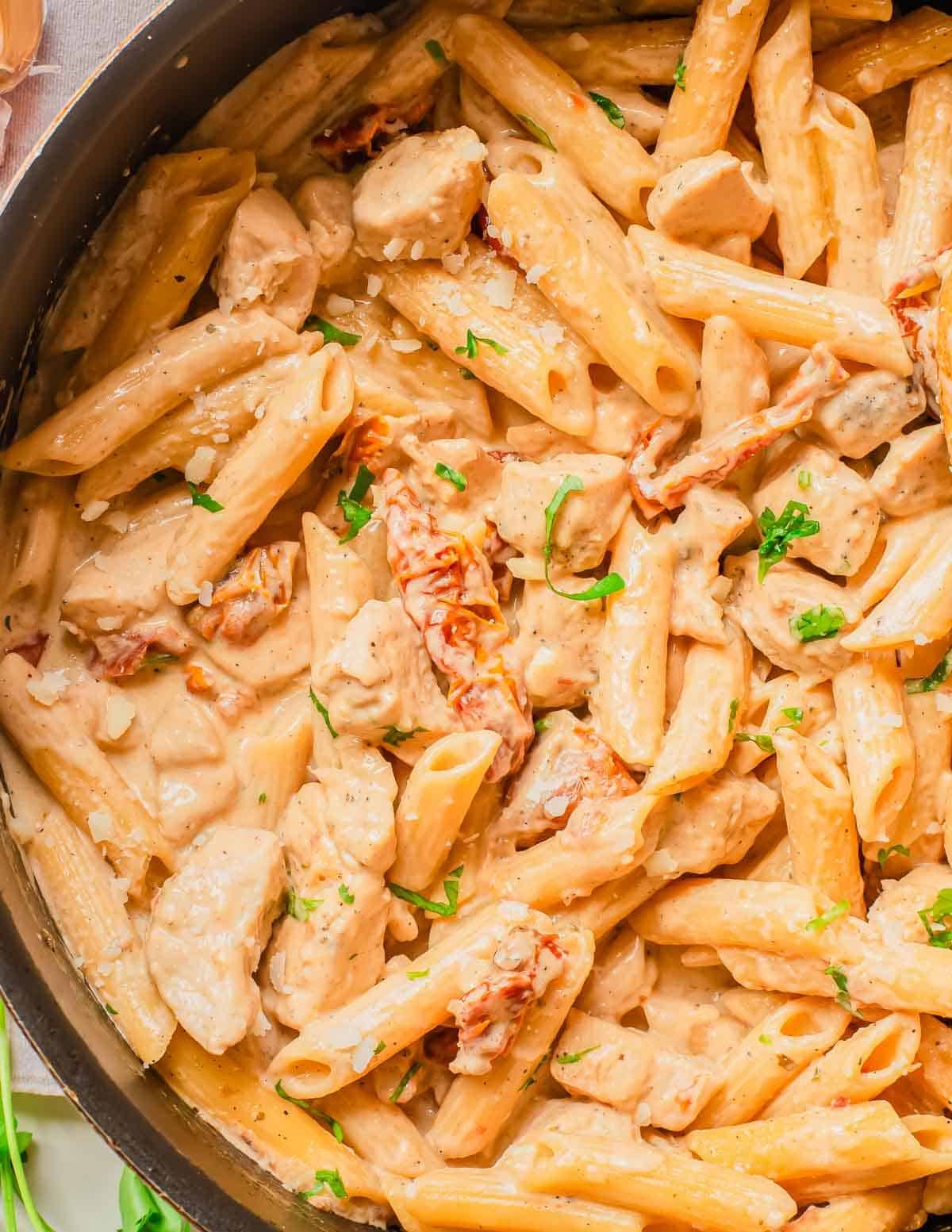 A cooking pan of marry me chicken pasta with creamy sauce and parsley.