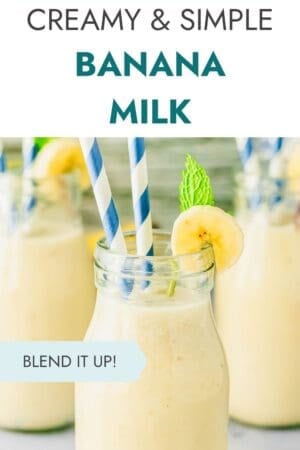 A glass of creamy banana milk garnished with a banana slice and mint, with two striped straws. More glasses are blurred in the background. Text reads: “Creamy & Simple Banana Milk” and “Blend It Up!”.