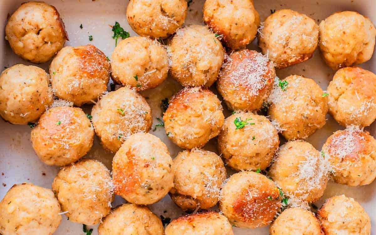 Bowl of baked chicken meatballs topped with grated cheese and herbs