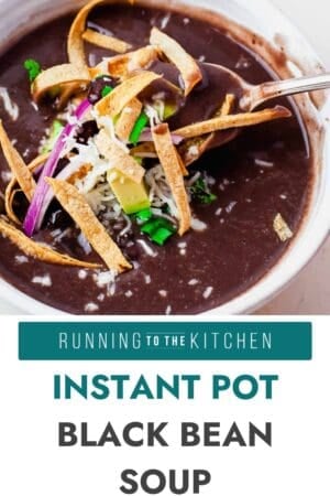 A bowl of black bean soup topped with tortilla strips, shredded cheese, diced avocado, cilantro, and red onion. A spoon rests in the bowl. Text below reads, “Instant Pot Black Bean Soup.”.