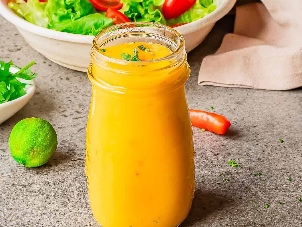 Mango sauce in a glass jar with lime and chili nearby
