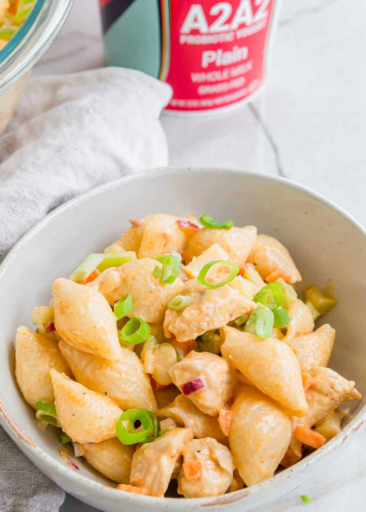 Creamy chicken potato salad garnished with green onions in a white bowl.