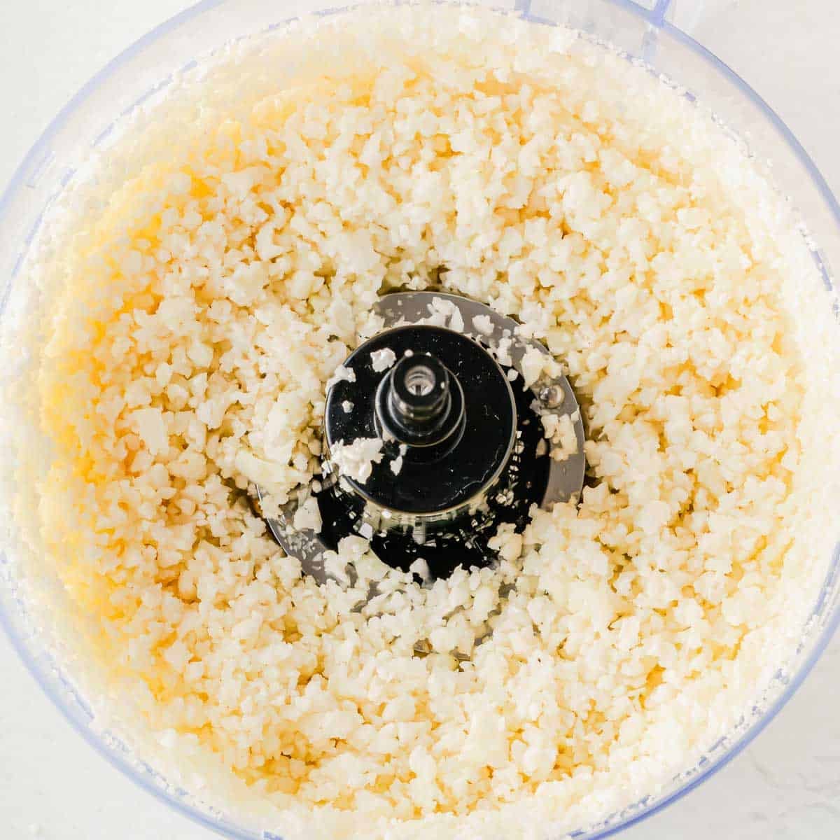 Processed cauliflower florets inside a food processor bowl.