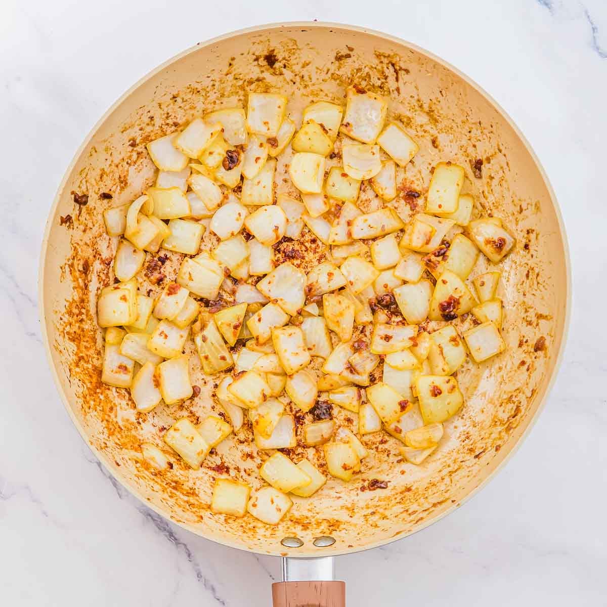 Diced onions sautéing in a non-stick skillet.